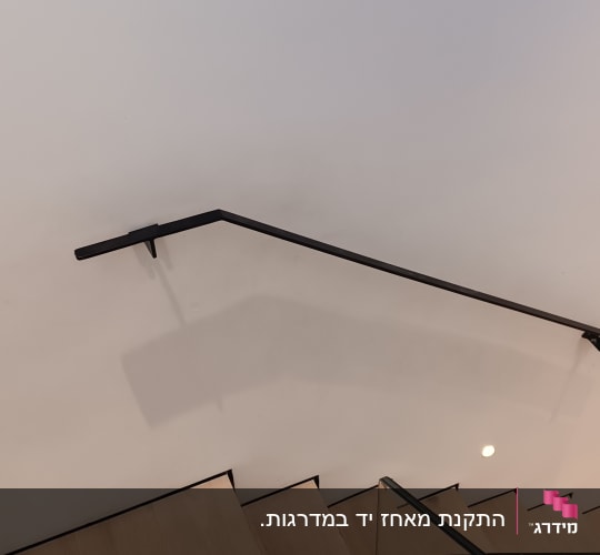 מעקה מתכת שחור ומסגרת זכוכית במדרגות עץ